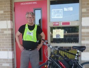 Robert E. Trudeau and his bike outside of his classroom.