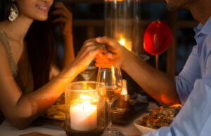 Explore Love and Singleness with Local Valentine’s Day Events in 2023 Romantic couple holding hands together over candlelight during romantic dinner